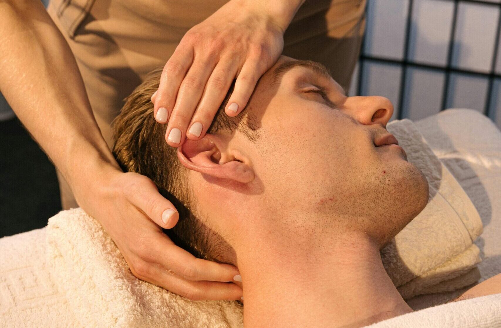 Close-up of a man receiving a relaxing head massage in a tranquil spa environment.
