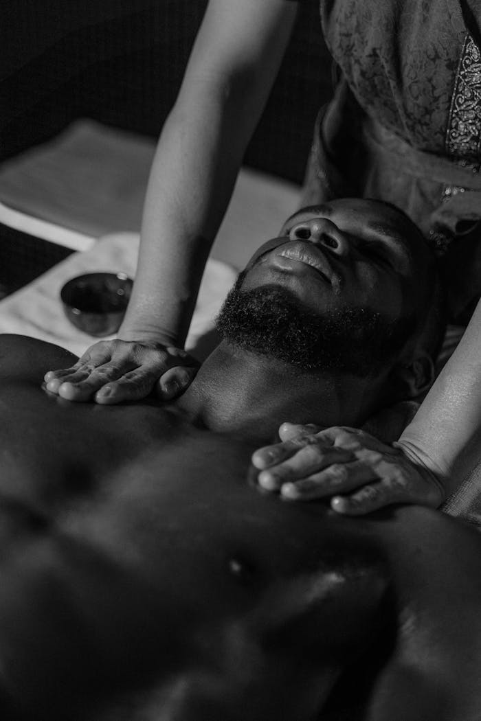 Black and white photo of a man receiving a relaxing massage promoting self-care and wellness.