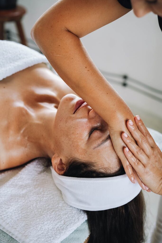 A serene spa experience featuring a woman receiving a calming face massage to promote relaxation and wellness.